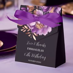 an elegant purple and black wedding card with flowers on it, tied in a ribbon