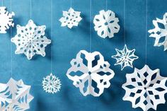 paper snowflakes hanging from strings on a blue wall