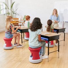 several children sitting at desks in front of a whiteboard