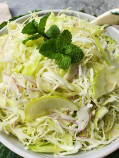 a white bowl filled with coleslaw and apple slices on top of a table