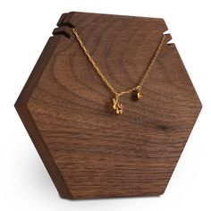 a wooden box with a gold necklace on it and two small charms hanging from the front