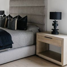 a bedroom with a bed, night stand and two lamps on either side of the bed