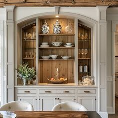 a kitchen with white cabinets and wooden shelves filled with dishes on top of each shelf