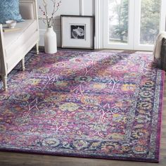 a colorful area rug with an ornate design on the center and bottom, in front of a window