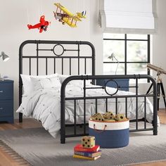 a bed room with a neatly made bed and toy airplanes hanging from the ceiling