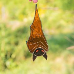 a stained glass bird feeder hanging from a branch with a pink flower in the foreground