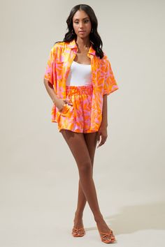 Brb, off to somewhere tropical with a drink in hand. The ideal vacation button up is here. A bright pink and orange tropical print decorates the Otto shirt. A classic collared top with a functional button front. It maintains a relaxed boyfriend fit and can easily be paired with your favorite bottoms or make it a set with the matching shorts.- Satin- Boyfriend fit- Pockets- Functional buttons- Color: Orange MultiSize + Fit - Model is 5'10" and wearing size XS- Measurements taken from size S - Che Pink Collared Hawaiian Shirt For Beach, Pink Collared Hawaiian Shirt For Vacation, Orange Short Sleeve Hawaiian Shirt For Spring, Orange Collared Camp Shirt For Summer, Orange Short Sleeve Camp Shirt For Vacation, Orange Hawaiian Shirt For Spring Vacation, Pink Hawaiian Shirt For Summer Beach, Summer Printed Pink Camp Shirt, Summer Orange Relaxed Fit Hawaiian Shirt