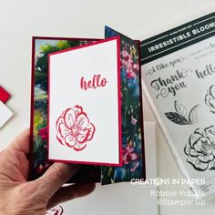 a hand holding an open card with flowers on it