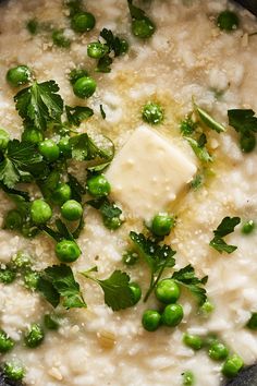 a bowl filled with rice and peas covered in parmesan cheese, garnished with green leaves