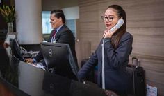 a woman talking on the phone while standing in front of a desk with a laptop