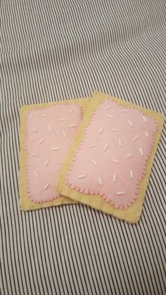 two pink and yellow squares with sprinkles on them sitting on a bed