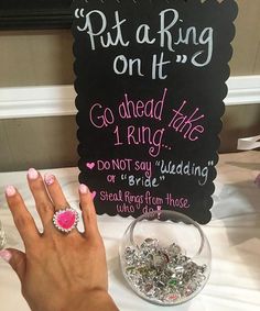 a woman's hand with pink nail polish next to a sign that says put a ring on it