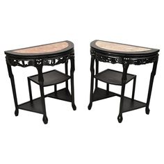 a pair of black tables with marble top