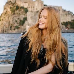 a woman with long red hair sitting on a boat