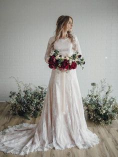 a woman in a wedding dress holding a bouquet of flowers and looking off into the distance