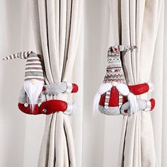 two christmas decorations hanging from curtains in front of white drapes with red and gray trim