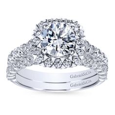 a white gold engagement ring with diamonds on the band and an oval center stone surrounded by round