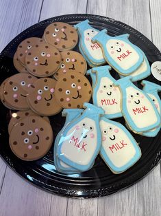 some cookies are on a black plate with white and blue icing, along with other decorated cookies