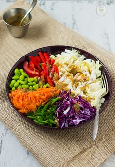 a bowl filled with different types of vegetables on top of a table next to a measuring cup