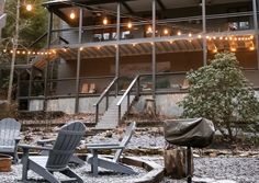 two adiron chairs sitting in front of a building with lights strung from the roof