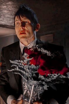 a man in a suit holding a bouquet of flowers