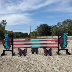 three benches with butterflies on them sitting in the sand