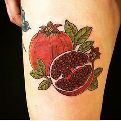 a woman's thigh with pomegranates and leaves on it