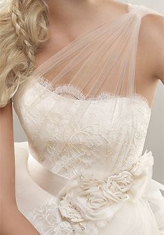 a woman in a wedding dress with a veil on her head and the words, this sheer one shoulder gown is a winner