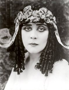 an old photo of a woman with braids in her hair wearing a headdress