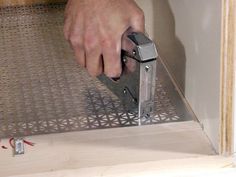 a person is using a tool to cut metal grates on a piece of plywood