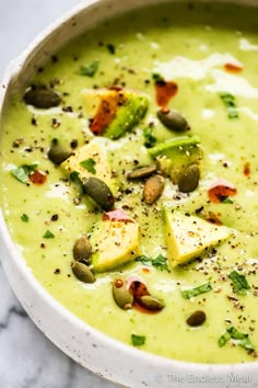 a white bowl filled with broccoli soup and topped with pistachios