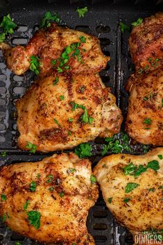 four pieces of chicken sitting on top of a grill with parsley sprigs