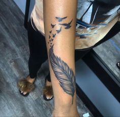 a woman's arm with a tattoo on it and birds flying around the feather