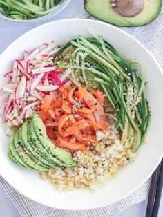 a white bowl filled with rice and veggies next to sliced avocado