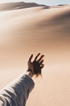 a person reaching out to touch sand in the desert