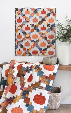 an orange and blue quilt sitting on top of a wooden table next to a potted plant