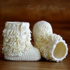 a pair of white crocheted baby booties on top of a wooden table