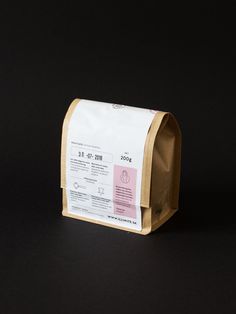 a brown paper bag sitting on top of a black table next to a white and pink sticker