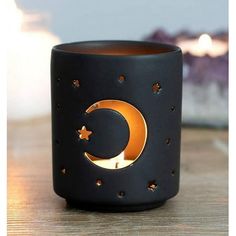 a black candle holder with a crescent and stars design on it sitting on a wooden table