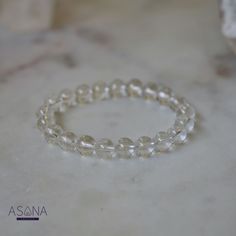 Introducing Asana Crystals' Clear Quartz Bracelet—a timeless and versatile accessory that embodies clarity, purity, and positive energy. Handcrafted from natural Clear Quartz, each bead in this bracelet exudes a pristine transparency symbolizing clarity of mind and spirit. Known as the "master healer," Clear Quartz amplifies energy, enhances intuition, and promotes overall well-being. Featuring smooth, round beads measuring 8mm, this bracelet offers a classic elegance suitable for any style or occasion. With no closure, the beaded stretch design ensures effortless wearability and comfort, allowing you to carry the uplifting energy of Clear Quartz throughout your day. Embrace the pure and transformative energy of Clear Quartz and elevate your look with Asana Crystals' Clear Quartz Bracelet— Holistic Round Beaded Bracelets For Meditation, Holistic Beaded Bracelets For Meditation, Adjustable Round Crystal Bracelet For Meditation, Spiritual Clear Round Beaded Bracelets, Clear Spiritual Beaded Bracelets, Adjustable Clear Round Bead Crystals, Spiritual Faceted Beaded Bracelets, Minimalist Round Crystal Bracelet With Gemstone Beads, Elegant Crystal Bracelet With 8mm Beads For Meditation