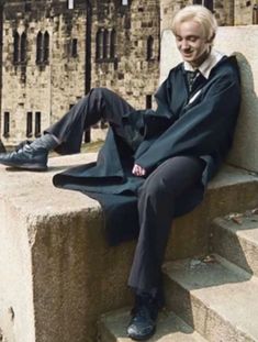 a person sitting on some steps wearing a coat and tie