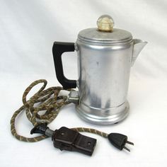 a silver coffee pot sitting on top of a white table next to a charger