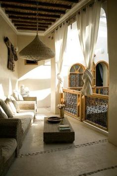 a living room filled with lots of furniture next to a wall covered in windows and curtains