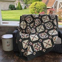 a black and white quilt sitting on top of a wicker chair next to a bucket