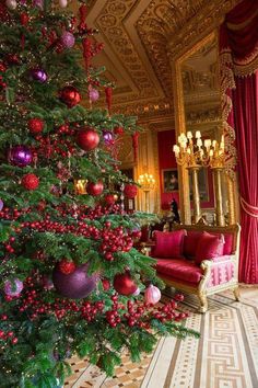 a christmas tree in the middle of a room with red and purple ornaments on it