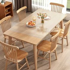 a dining room table with chairs and a plate of fruit on the table next to it