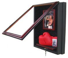 a red boxing glove is in a black box with a wooden frame on the wall