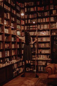 a woman standing on a ladder in front of a bookshelf