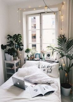 a white bed sitting under a window next to a potted plant