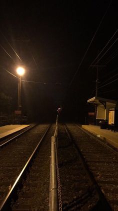 an empty train track at night with the lights on and no one is in it